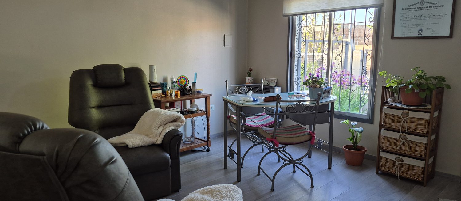 Consultorio en Barrio Los Eucaliptos, Juana Koslay: sillón, mesa junto a la ventana y plantas